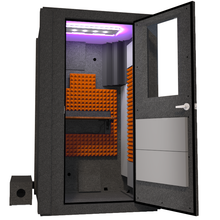 Load image into Gallery viewer, Angled view of the WhisperRoom&#39;s Voice Over Basic Package - a 4&#39; x 4&#39; single-wall vocal booth, expertly equipped with acoustic treatment, a functional desk, studio lighting, and an array of premium features. The right-hinged door is open, revealing the interior enhanced by vibrant orange StudioFoam, creating an ideal recording atmosphere.
