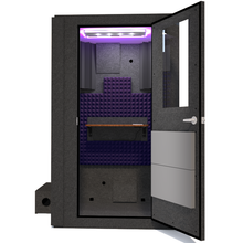 Load image into Gallery viewer, Front view of WhisperRoom&#39;s Voice Over Basic Package - a 4&#39; x 4&#39; single-wall vocal booth, meticulously designed with acoustic treatment, a functional desk, studio lighting, and a comprehensive range of premium features. The right-hinged door is open, revealing the interior accentuated with elegant purple StudioFoam, creating an inviting and professional recording environment.
