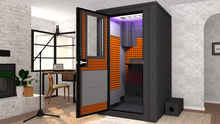 Load image into Gallery viewer, WhisperRoom&#39;s Voice Over Deluxe Package: A 4&#39;x4&#39; Double-Wall Vocal Booth equipped with Bass Traps, a Folding Office Desk, Orange Auralex StudioFoam, an Exterior Fan Silencer, Multi-Colored LED Studio Light, and an Acoustic Package, perfectly integrated into a living room home recording studio setup next to a fireplace with a chair at a desk, a laptop, and a complete various other equipment for voiceover.

