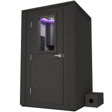 Load image into Gallery viewer, Angled view of WhisperRoom&#39;s Voice Over Deluxe Package - a 4&#39; x 4&#39; double-wall vocal booth, meticulously designed with acoustic treatment, a functional desk, studio lighting, and a comprehensive range of premium features. The left-hinged door is closed, and the interior is enhanced by sophisticated gray StudioFoam, creating an ideal recording environment.
