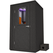 Load image into Gallery viewer, Frontal view of WhisperRoom&#39;s Voice Over Deluxe Package - a 4&#39; x 4&#39; double-wall vocal booth, meticulously designed with acoustic treatment, a functional desk, studio lighting, and a comprehensive range of premium features. The left-hinged door is closed, and the interior is enhanced by vibrant orange StudioFoam, creating an ideal recording environment.
