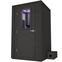 Load image into Gallery viewer, Angled view of WhisperRoom&#39;s Voice Over Deluxe Package - a 4&#39; x 4&#39; double-wall vocal booth, meticulously designed with acoustic treatment, a functional desk, studio lighting, and a comprehensive range of premium features. The left-hinged door is closed, and the interior is enhanced by elegant purple StudioFoam, creating an ideal recording environment.
