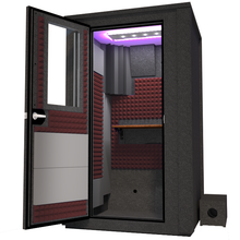 Load image into Gallery viewer, Angled view of the WhisperRoom&#39;s Voice Over Deluxe Package - a 4&#39; x 4&#39; double-wall vocal booth, thoughtfully equipped with acoustic treatment, a functional desk, studio lighting, and an array of premium features. The left-hinged door is open, revealing the interior enhanced by sophisticated burgundy StudioFoam, creating an ideal recording atmosphere.
