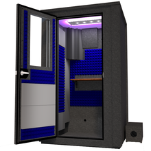 Load image into Gallery viewer, Angled view of the WhisperRoom&#39;s Voice Over Deluxe Package - a 4&#39; x 4&#39; double-wall vocal booth, thoughtfully equipped with acoustic treatment, a functional desk, studio lighting, and a comprehensive range of premium features. The left-hinged door is open, revealing the interior accentuated with vibrant blue StudioFoam, creating an ideal recording atmosphere.
