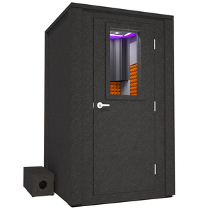 Frontal view of WhisperRoom's Voice Over Deluxe Package - a 4' x 4' double-wall vocal booth, meticulously designed with acoustic treatment, a functional desk, studio lighting, and a comprehensive range of premium features. The right-hinged door is closed, and the interior is enhanced by vibrant orange StudioFoam, creating an ideal recording environment.