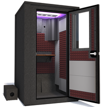 Load image into Gallery viewer, Angled view of WhisperRoom&#39;s Voice Over Deluxe Package - a 4&#39; x 4&#39; double-wall vocal booth, meticulously designed with acoustic treatment, a functional desk, studio lighting, and a comprehensive range of premium features. The right-hinged door is open, revealing the interior enhanced by sophisticated burgundy StudioFoam, creating an ideal recording atmosphere.
