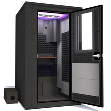 Load image into Gallery viewer, Angled view of the WhisperRoom&#39;s Voice Over Deluxe Package - a 4&#39; x 4&#39; double-wall vocal booth, thoughtfully equipped with acoustic treatment, a functional desk, studio lighting, and an array of premium features. The right-hinged door is open, revealing the interior enhanced by sophisticated gray StudioFoam, creating an ideal recording atmosphere.
