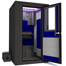 Load image into Gallery viewer, Angled view of the WhisperRoom&#39;s Voice Over Deluxe Package - a 4&#39; x 4&#39; double-wall vocal booth, meticulously designed with acoustic treatment, a functional desk, studio lighting, and a comprehensive range of premium features. The right-hinged door is open, and the interior is accentuated with vibrant blue StudioFoam, creating an ideal recording environment.
